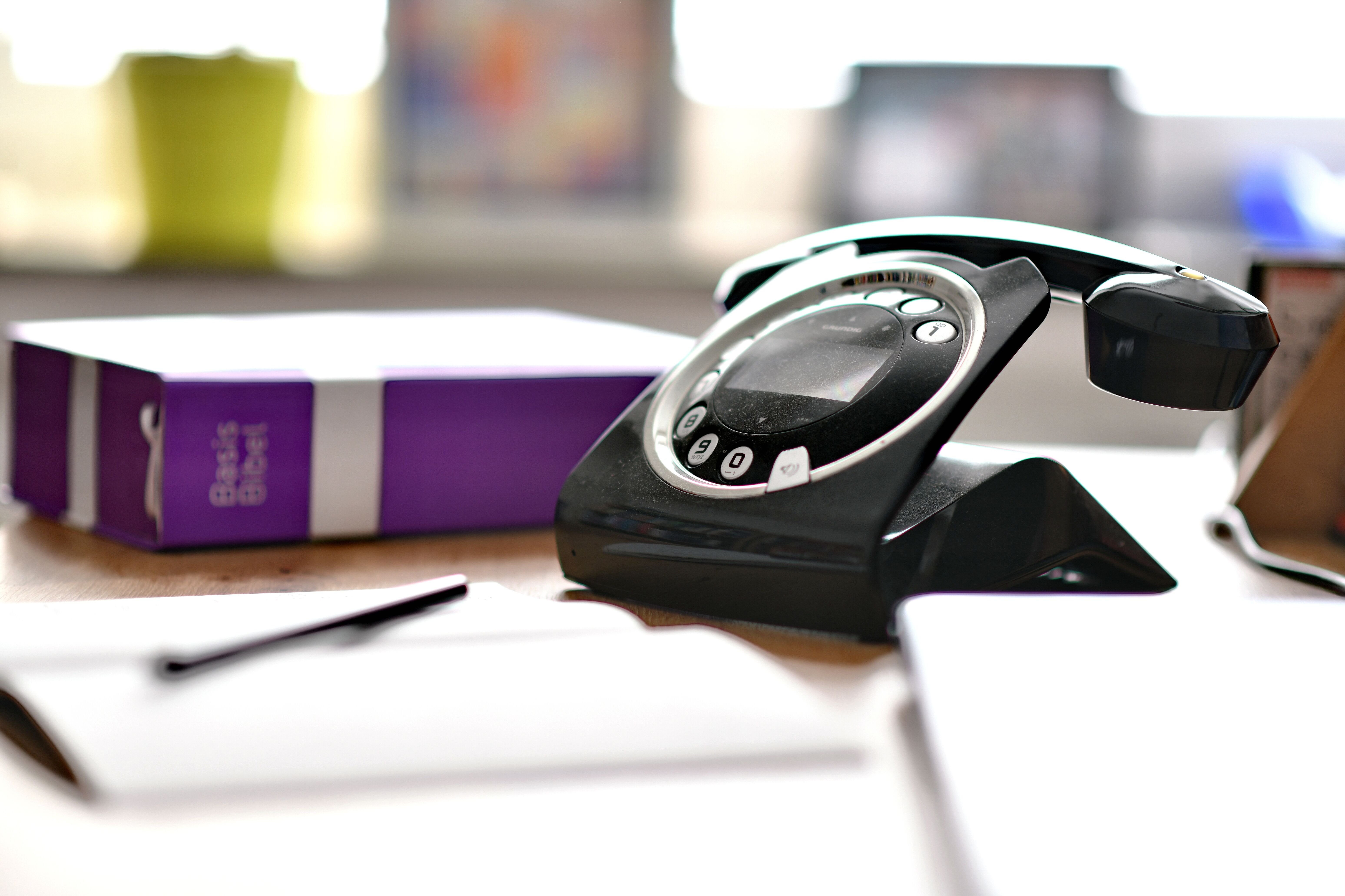 Schreibtisch mit Notizblock,Kugelschreiber, Basisbibel und einem Telefon. Verschwommener Hintergrund